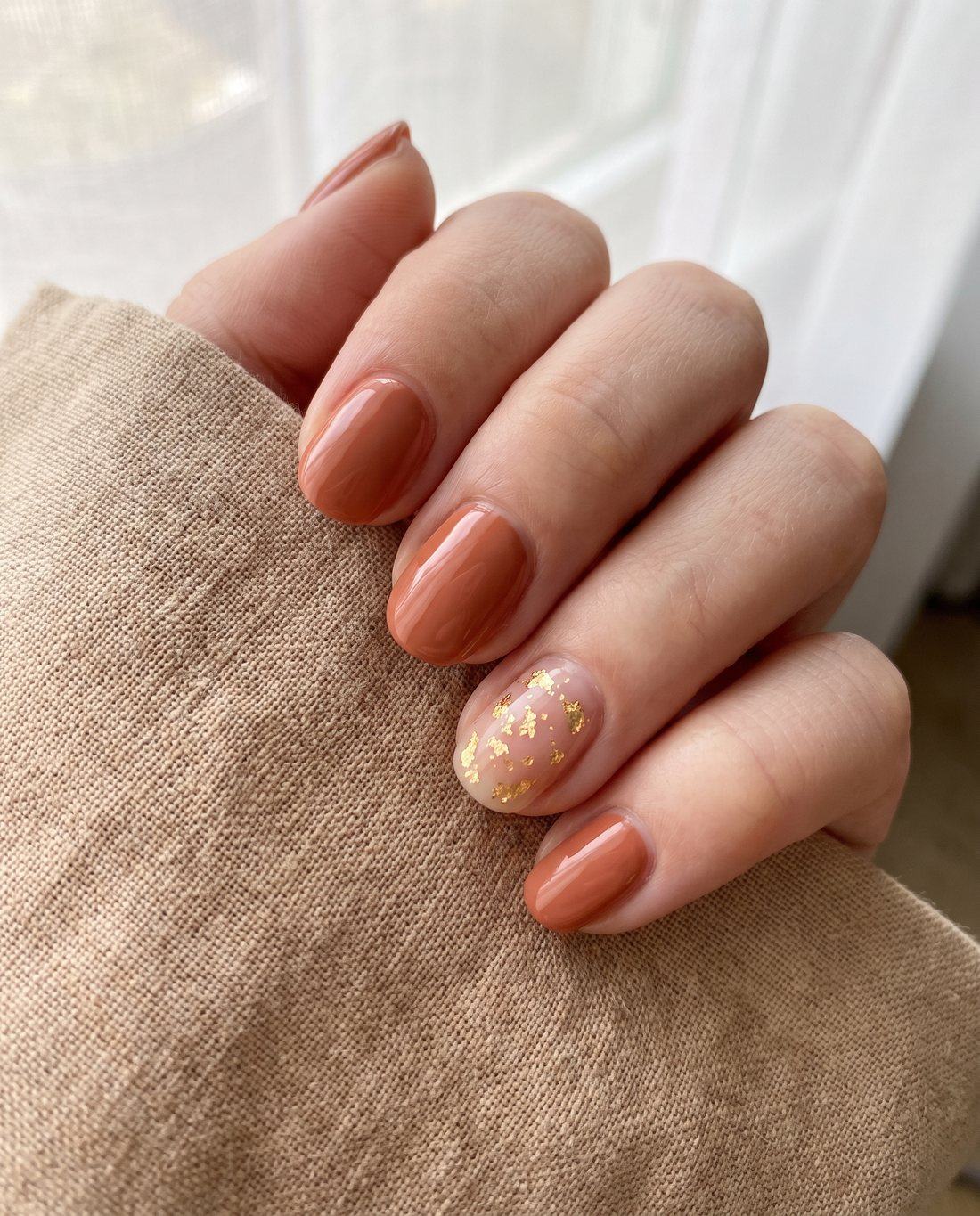 Warme terracotta gellak met een gouden accentnagel